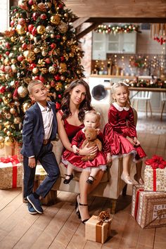 a family sitting on a couch in front of a christmas tree with presents around it