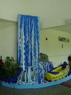 an inflatable water slide with blue and white streamers on the wall next to it