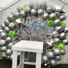 a bunch of balloons that are in front of a white table and some silver stars