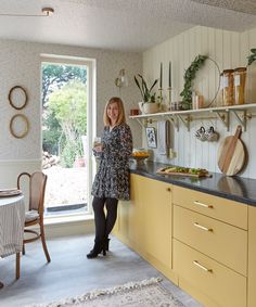 a woman standing in a kitchen next to a window