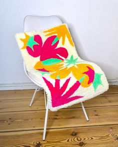 a white chair with a colorful flower design on the back and seat cover, sitting in a room