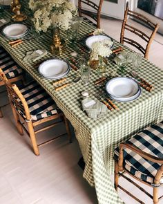 the table is set with green and white checkered cloths, place settings, and flowers