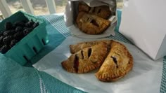 three pastries sitting on top of a table next to a box of blackberries