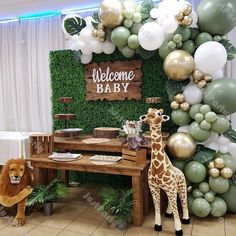 a baby shower is decorated with balloons, greenery and giraffe figurines