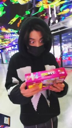 a person wearing a black hoodie holding a pink package