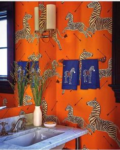 an orange bathroom with zebras on the wall and blue towels hanging from the hooks