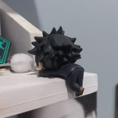 a close up of a black and white animal head on a window sill next to a sign