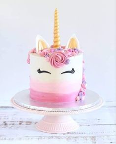 a pink and white cake with a unicorn face on top