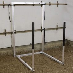 a white wall with two metal bars in front of it and some dirt on the ground