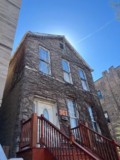 an old brick building with stairs leading up to the front door and number on it