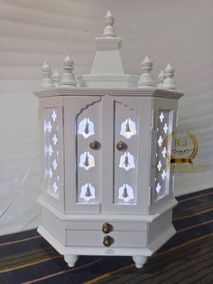 a white cabinet with bells on the doors and drawers is shown in front of a wall