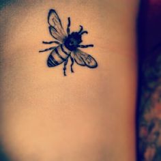 a bee tattoo on the back of a woman's leg, with an insect drawn on it