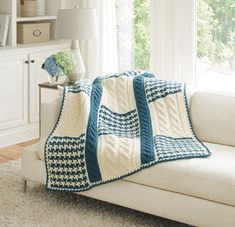 a white couch with a blue and white crocheted afghan on top of it