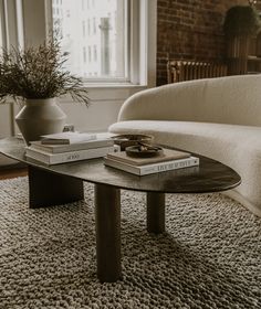 a coffee table with two books on it in front of a window and a couch