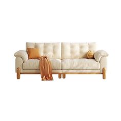 a white couch sitting on top of a wooden floor next to a pillow and blanket