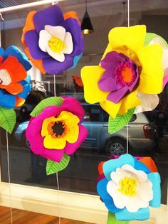 colorful paper flowers hanging from strings in front of a window