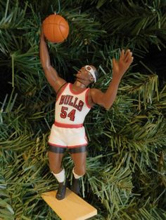 a basketball player ornament hanging on a christmas tree with his arms in the air