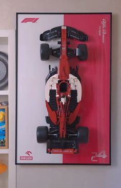 a red and white race car on display in front of a wall with other toys