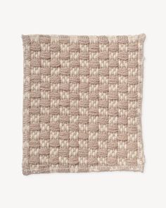 a beige and white knitted pillow on a white background, with small squares in the middle