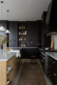 a kitchen with black cabinets and an area rug on the floor in front of it