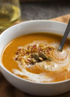 a white bowl filled with soup and garnished with nuts