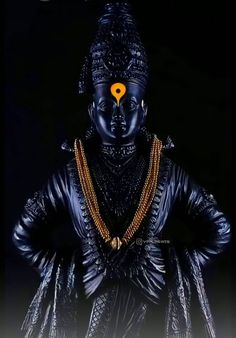 a black statue with a yellow marker on it's forehead and head in the shape of a buddha