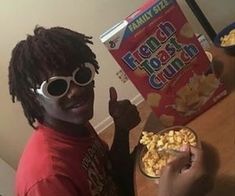 a young man wearing sunglasses and holding a bowl of cereal in front of his face