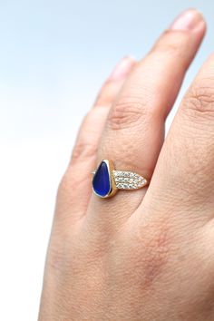 a woman's hand with a ring on it and a blue stone in the middle