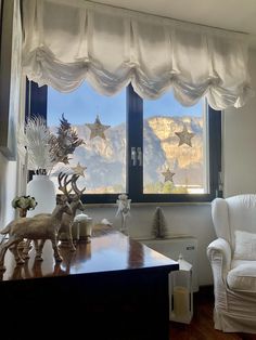 a living room filled with furniture and a window covered in white curtained valances