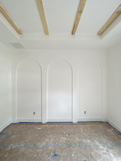 an empty room with white walls and blue tape on the floor in front of three arched doorways