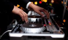 two people are playing music on a dj's turntable in front of blurry lights