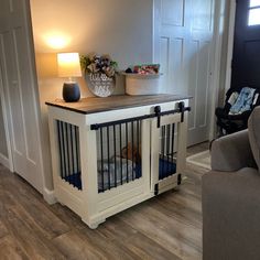 a dog is in his cage at the end of the living room table, which also has a lamp on it