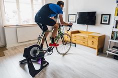 a man riding a bike on top of a stationary exercise bike in a living room