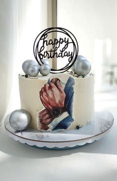 a birthday cake decorated with an image of a man's hand and two silver balls