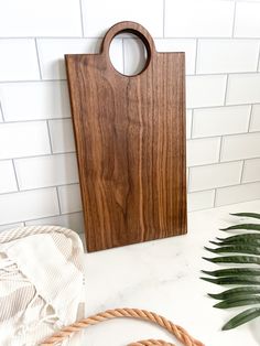 a wooden cutting board sitting on top of a counter next to a rope and potted plant