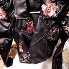 This Black Faux Leather Embroidery Jacket Is So Gorgeous With The Big Flowers And The Decor All Over And Silver/Gray Stud Decor Down Back And End Of Sleeves. Like New ,Zips In Front And End Sleeves Open And Close Zip For Comfort. Size M, 23" Sleeves 20" L Stunning Winter Embellished Leather Jacket With Long Sleeves, Fall Outerwear With Floral Applique And Long Sleeves, Fall Long Sleeve Outerwear With Floral Applique, Embellished Long Sleeve Biker Jacket For Fall, Fall Floral Applique Long Sleeve Outerwear, Fitted Leather Jacket With Floral Embroidery For Winter, Winter Floral Embroidered Fitted Leather Jacket, Winter Embellished Long Sleeve Biker Jacket, Embellished Long Sleeve Biker Jacket For Winter