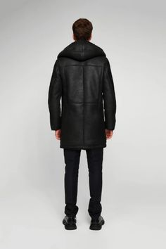 Men's Hooded Shearling Leather Coat In Black Wrap yourself in the luxurious warmth of this men's hooded shearling leather coat in sophisticated black. Expertly crafted from genuine sheepskin leather with a semi-aniline finish, this coat features a plush faux shearling inner shell. The stylish button closure, hooded collar, and open hem cuffs with shearling detail combine functionality with fashion. With two side pockets for convenience, this coat is the epitome of winter elegance and comfort. Ou Luxury Black Sheepskin Fur Coat, Luxury Hooded Fur Coat For Cold Weather, Luxury Black Hooded Leather Jacket, Black Hooded Fur Coat With Detachable Hood, Black Sheepskin Long Coat, Black Shearling Fur Coat For Cold Weather, Black Sheepskin Fur Coat For Cold Weather, Luxury Leather Coat For Cold Weather, Luxury Black Parka For Winter