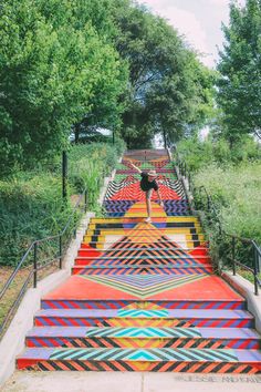 a man is walking down some colorful stairs with trees in the backgroup