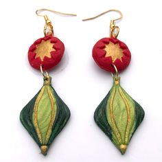 pair of red and green earrings with gold accents on white background, close - up