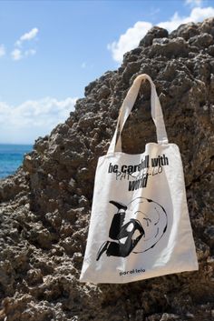 a tote bag sitting on top of a rock near the ocean