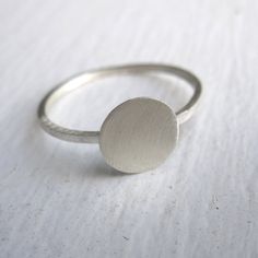 The Tiny Silver flat disk Ring is perfect for everyday wear. The design of this ring is very elegant and simple. The ring has a smooth, matte finish and the width of the band is 1 mm. The tiny flat disk has a diameter of 7mm. This ring is a perfect for stacking. Package in a brown kraft box. Minimalist Rings With Brushed Finish For Gift, Minimalist Rings With Brushed Finish As Gift, Minimalist Brushed Finish Promise Ring, Minimalist Everyday Jewelry With Brushed Finish, Minimalist Rings With Brushed Finish For Anniversary, Silver Minimalist Jewelry With Brushed Finish, Minimalist Rounded Jewelry With Smooth Finish, Minimalist Ring With Smooth Finish, Minimalist Everyday Rings With Smooth Finish