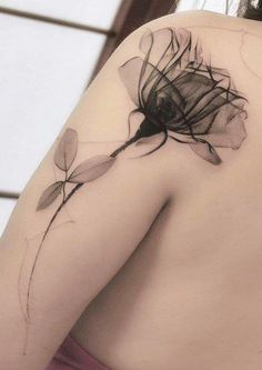 the back of a woman's shoulder with a flower tattoo on her left arm