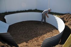 a man is standing in the middle of a large circular garden bed that's being built