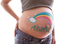 a pregnant woman's stomach with the word rainbow painted on it