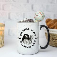 there is a coffee mug with an ice cream ball on it and the words, i'm still in my halloween mood