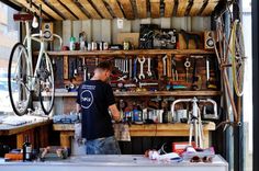 a man standing in front of a bike shop filled with lots of tools and equipment