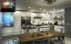 a modern kitchen with stainless steel appliances and wooden dining table surrounded by white chairs, an island that has fruit on it