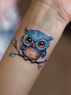 an owl tattoo is on the wrist of a woman's arm and it looks like she has been painted