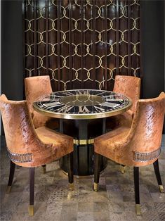 two chairs and a table in front of a wall with gold circles on it's sides