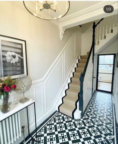 a black and white checkered floor in a house with stairs leading up to the second floor